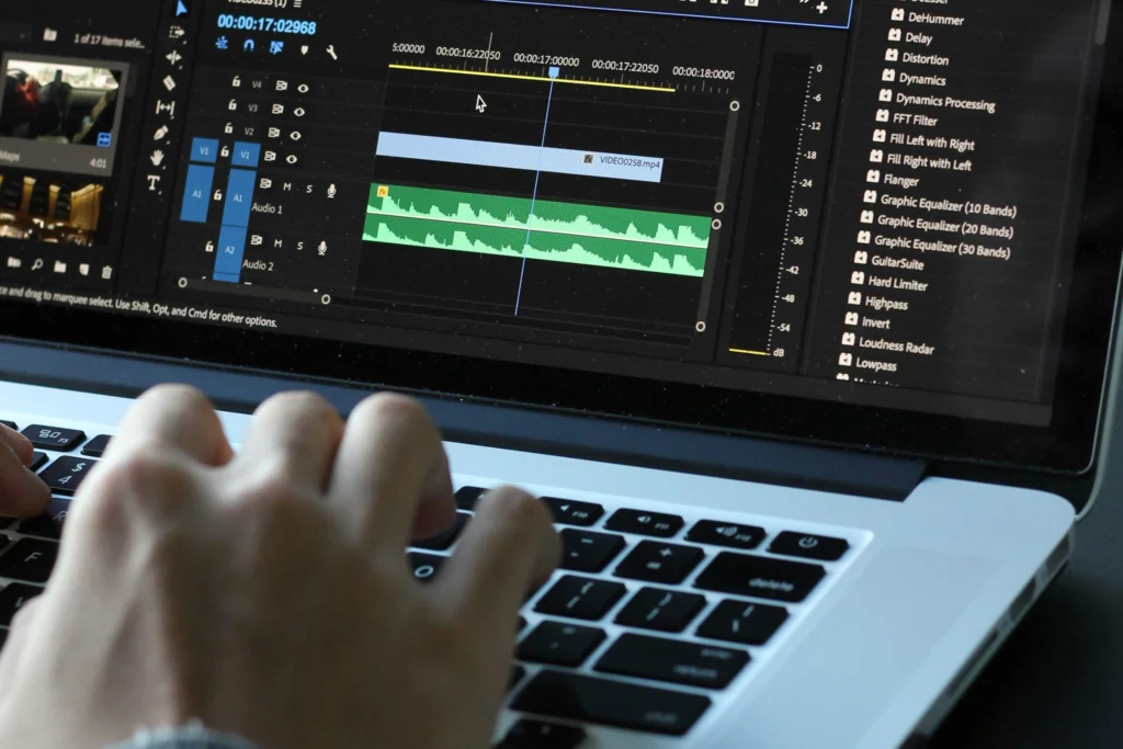 Osoba montująca film w programie Adobe Premiere Pro na laptopie.